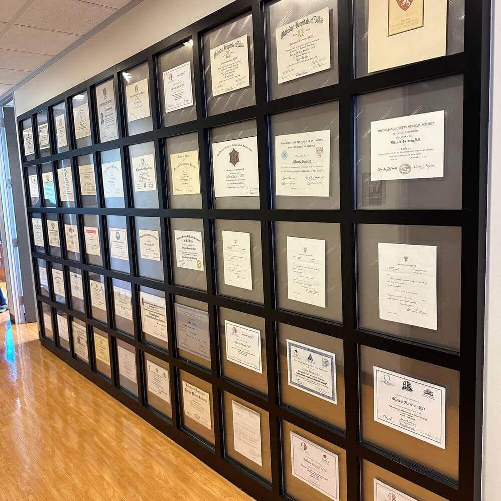 Mur de certificats encadrés dans un cabinet moderne de réflexologie plantaire thérapeutique, témoignant des qualifications et de l'expertise du praticien.